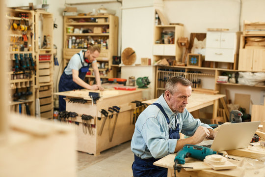 High angle portrait of two carpenters working with wood standing at tables in workshop, copy space