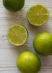 Fototapeta na wymiar Green citrus limes on a white wooden background, top view. From above, overhead, flat lay. Close-up.