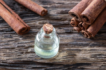 A bottle of cinnamon essential oil with cinnamon sticks