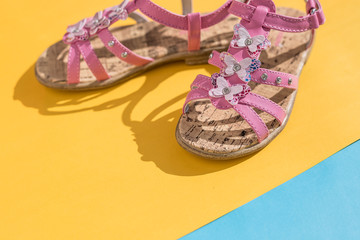 Pink colored shoes on pastel yellow and blue background, minimalistic summer fashion concept....