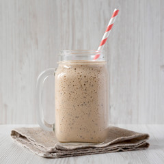 Glass jar mug filled with banana, kiwi, apple smoothie, side view. Closeup.