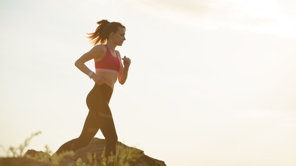 Young Beautiful Woman Running on the Mountain Trail at Hot Summer Sunset. Sport and Active Lifestyle.