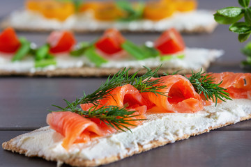 Crispbread with soft cheese, trout and dill, close-up. Easy summer snack. Light picture.