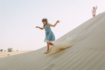 Fototapeta na wymiar Two little sisters running in the desert and having fun