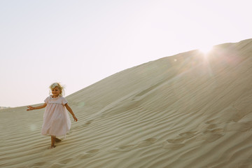 Fototapeta na wymiar Little girl walking on a dune in the desert