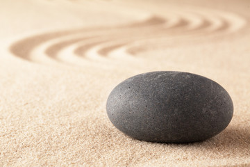 Fototapeta na wymiar Spiritual stone therapy, black basalt round rock on sandy background. Spa wellness treatment.