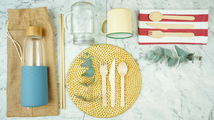 Zero-waste, plastic-free tableware flatlay overhead with bamboo and natural fibers to replace single use plastic products.
