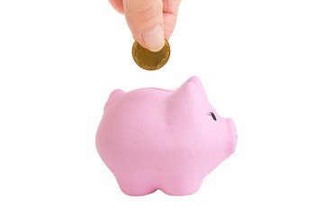 Female hand putting a coin into piggy bank on white isolated background. Pink piggy bank.