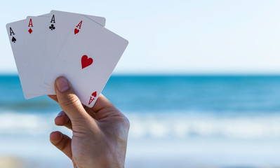 Card game outdoors at beach, four aces in the player's hand