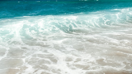Fototapeta na wymiar Beautiful image of turquoise sea waves rolling over the shore at bright sunny day
