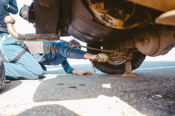 man lies under a 4x4 car on a dirt road