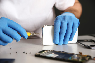 Technician repairing mobile phone at table, closeup