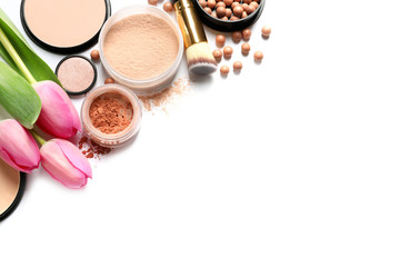 Many different makeup products and spring flowers on white background, top view