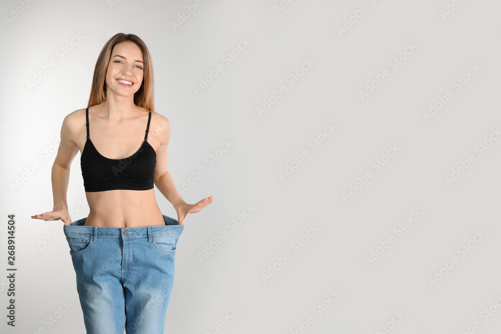 Sticker Slim woman in oversized jeans on light background, space for text. Perfect body