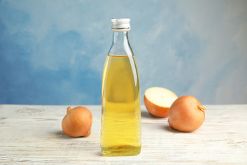 Glass bottle of onion syrup and fresh vegetable on table