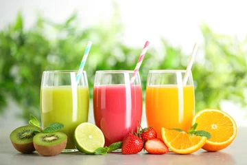 Fototapeten Glasses of different juices with straws and fresh fruits on table against blurred background © New Africa