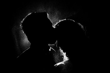 portrait silhouette photo of a couple in a kiss under water drops