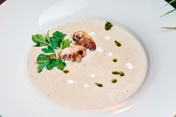 mushroom cream soup with cream, garnished with fried champignon slices and parsley in a beautiful white plate. Close-up