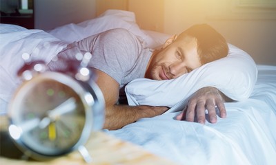 man wide awake in bed staring at
