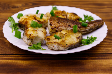 Roasted pollock in white plate on a wooden table