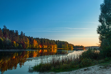 Silence at the forest lake at sunset, with reflection of sky and forest on a water smooth surface, Russia, Mari El