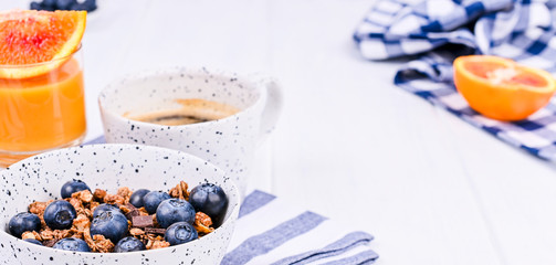 Breakfast on a white background. Fragrant coffee, orange juice and muesli with berries. Banner