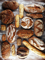 Different kinds of bread and bread rolls on board from above. Kitchen or bakery