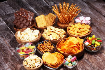Salty snacks. Pretzels, chips, crackers in wooden bowls on table