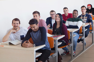 University students listening while Male professor explain lesson to them and interact with them in the classroom.