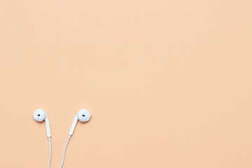 Headphones on a pastel background. White headphones on a peach background. View from above. Copy space Trendy colorful photo. Minimal style with colorful paper background. Music concept