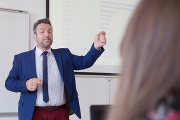 Male professor explain lesson to students and interact with them in the classroom.Helping a students during class. University student being helped by male lecturer during class.