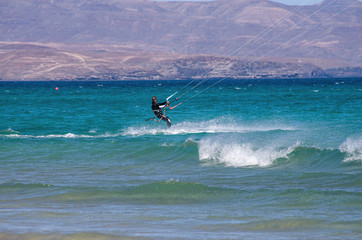 fuerteventura - canary islands, kitesurfer rides the waves using the speed of the wind