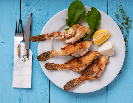 Red scorpionfish is cooked in oil. served with arugula, lemon and onion