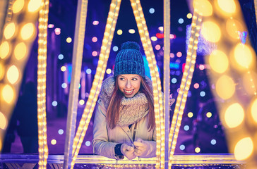 Portrait of a young woman in winter clothing enjoying christmas lighting in Vigo - obrazy, fototapety, plakaty