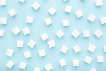Abstract pattern made of sugar cubes scattered on blue background