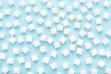 Abstract pattern made of sugar cubes scattered on light blue background