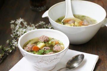 soup with meatballs in a white bowl. light soup with pork meatballs.