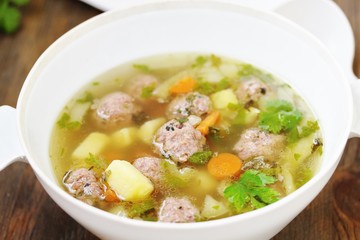 soup with meatballs in a white bowl. light soup with pork meatballs.