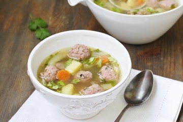 soup with meatballs in a white bowl. light soup with pork meatballs.