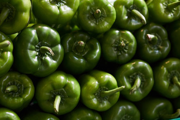 Fresh green bell peppers, paprika pile background, close-up