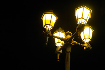 Vintage, traditional sodium vapor street lamp emitting yellow light at night in Faro, Algarve, Portugal