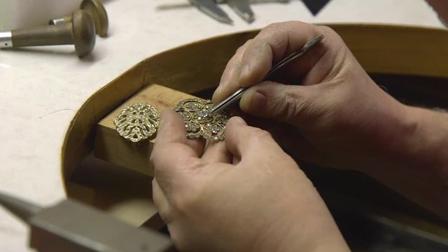 jeweler in the workshop fixes diamonds in brooches