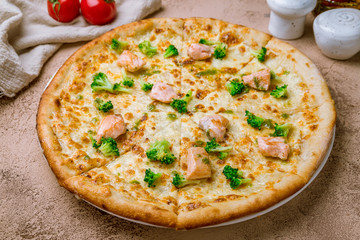 Pizza with salmon and broccoli on rustic table