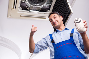 Young repairman repairing ceiling air conditioning unit 
