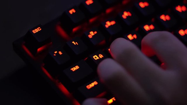 Computer keyboard with red backlight close-up with fingers play game using WASD keys (4K, 29fps)
