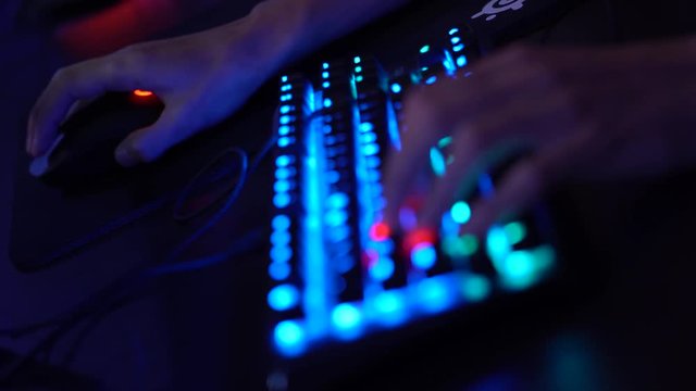 Gaming computer keypad with blue backlight with player hands on it with refocus to a mouse (4K, 29fps)