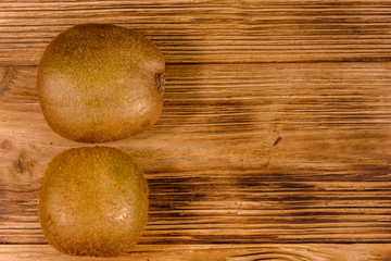Fototapeta na wymiar Two kiwi fruits on a wooden table. Top view