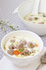 creamy soup with meatballs in a white bowl on the background of a gray tablecloth in polka dots. light soup with cream and pork meatballs. French style dishes. SWEDISH MEATBALLS