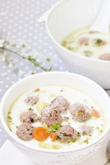 creamy soup with meatballs in a white bowl on the background of a gray tablecloth in polka dots. light soup with cream and pork meatballs. French style dishes. SWEDISH MEATBALLS