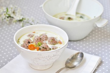 creamy soup with meatballs in a white bowl on the background of a gray tablecloth in polka dots. light soup with cream and pork meatballs. French style dishes. SWEDISH MEATBALLS